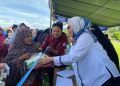 Bupati Merlan S. Uloli saat melayani warga yang membeli bahan pokok di pasar murah Kecamatan Suwawa Tengah, Rabu (7/2/2024). (F. Tim IKP)