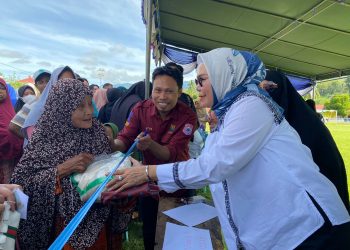 Bupati Merlan S. Uloli saat melayani warga yang membeli bahan pokok di pasar murah Kecamatan Suwawa Tengah, Rabu (7/2/2024). (F. Tim IKP)