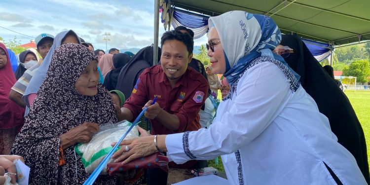 Bupati Merlan S. Uloli saat melayani warga yang membeli bahan pokok di pasar murah Kecamatan Suwawa Tengah, Rabu (7/2/2024). (F. Tim IKP)