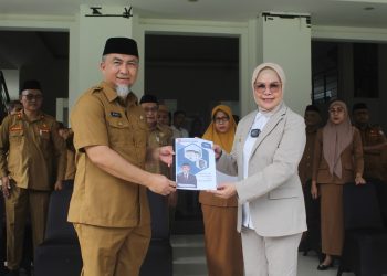 Pjs Bupati Bone Bolango 2024, Budiyanto Sidiki saat menyerahkan nota kinerja kepada Bupati Bone Bolango, Merlan S. Uloli pada pelaksaan apel kerja di lingkungan Pemerintah Kabupaten Bone Bolango, Senin (25/11/2024). (Foto Yudi/Prokopim)