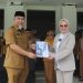 Pjs Bupati Bone Bolango 2024, Budiyanto Sidiki saat menyerahkan nota kinerja kepada Bupati Bone Bolango, Merlan S. Uloli pada pelaksaan apel kerja di lingkungan Pemerintah Kabupaten Bone Bolango, Senin (25/11/2024). (Foto Yudi/Prokopim)
