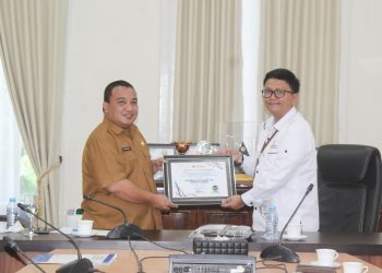 Pjs Kepala Ombudsman RI Perwakilan Provnsi Gorontalo, Lucky Puspito Rantung saat menyerahkan langsung piagam penghargaan penganugerahan predikat penilaian kepatuhan penyelenggaraan pelayanan publik tahun 2024 kepada Pemerintah Kabupaten Bone Bolango yang diterima langsung oleh Pj Sekretaris Daerah Bone Bolango Reflin Buata di Ruang Rapat Bupati Bone Bolango, Senin (16/12/2024). (Foto Yudi/Prokopim)
