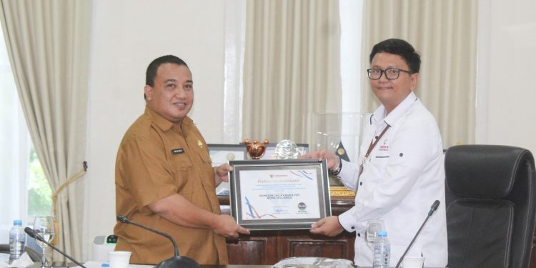 Pjs Kepala Ombudsman RI Perwakilan Provnsi Gorontalo, Lucky Puspito Rantung saat menyerahkan langsung piagam penghargaan penganugerahan predikat penilaian kepatuhan penyelenggaraan pelayanan publik tahun 2024 kepada Pemerintah Kabupaten Bone Bolango yang diterima langsung oleh Pj Sekretaris Daerah Bone Bolango Reflin Buata di Ruang Rapat Bupati Bone Bolango, Senin (16/12/2024). (Foto Yudi/Prokopim)