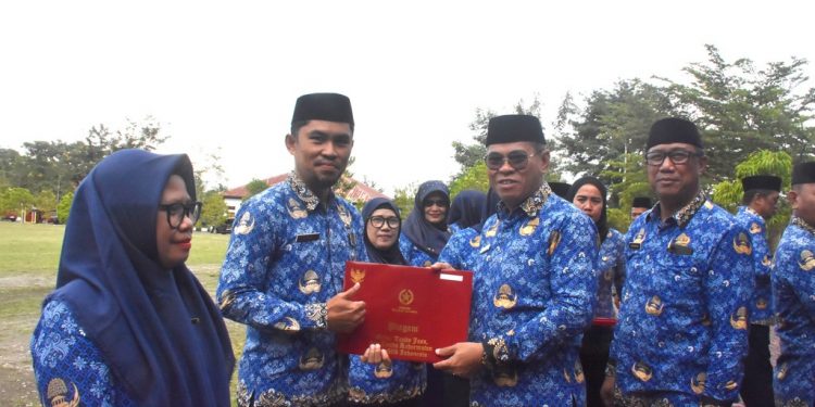 Sekda Iwan Mustapa saat menyerahkan penghargaan Satya Lencana kepada ASN saat memimpin Apel Korpri di Lapangan Alun-Alun Bone Bolango, Rabu (17/9/2025). (F. AKP/Diskominfo)