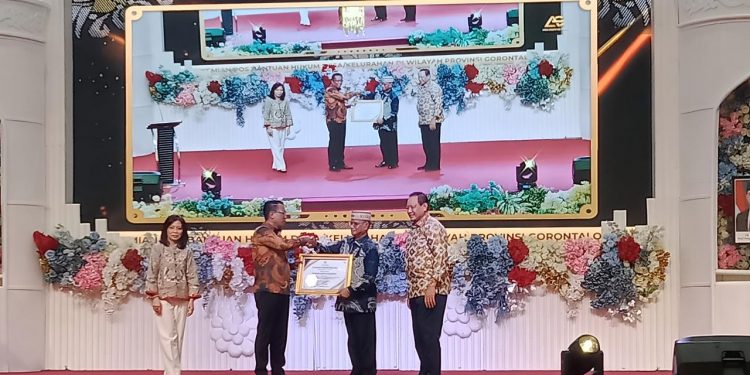 Bupati Ismet Mile didampingi Gubernur Gusnar Ismail saat menerima piagam penghargaan dari Menteri Hukum RI, Supratman Andi Agtas di Azlea Convention Center, Kota Gorontalo, Jumat (28/11/2025). (F.Sandi/Diskominfo)