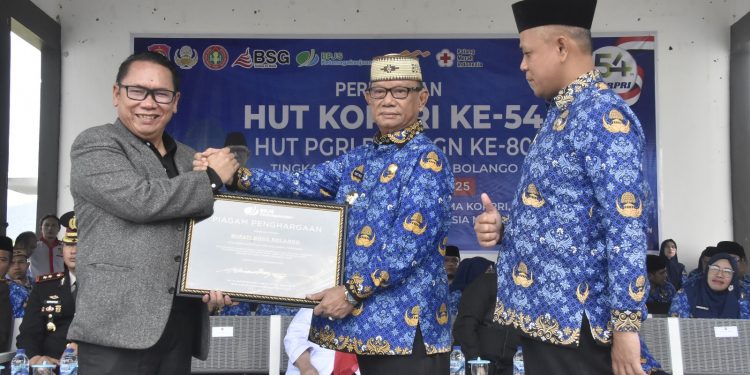 Bupati Ismet Mile saat menerima piagam penghargaan dari Kepala BPJS Ketenagakerjaan Gorontalo, Sanco Simanullang atas komitmennya melindungi seluruh Pengurus Koperasi Desa/Kelurahan Merah Putih (KDKMP) melalui program jaminan sosial ketenagakerjaan yang dibiayai langsung oleh APBD, Senin (1/12/2025). (F.Indra/Diskominfo)