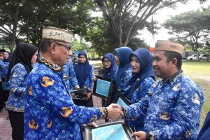 Bupati Bone Bolango, Ismet Mile, saat menyerahkan Penghargaan TOP IPASN Excellence Award 2025 kepada Abdul Kadir Pakaya, salah satu ASN pada Dinas Kominfo di sela Upacara HUT Korpri ke-54, HUT PGRI, dan Hari Guru ke-80 di Lapangan Alun-Alun Bone Bolango, Senin (1/12/2025). (F.Indra/Diskominfo)