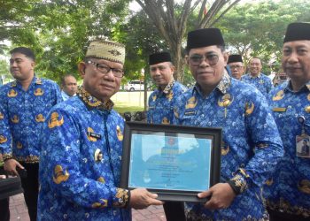 Bupati Bone Bolango, Ismet Mile, saat menyerahkan Penghargaan TOP IPASN Excellence Award 2025 kepada Sekda Iwan Mustapa di sela Upacara HUT Korpri ke-54, HUT PGRI, dan Hari Guru ke-80 di Lapangan Alun-Alun Bone Bolango, Senin (1/12/2025). (F.Indra/Diskominfo)