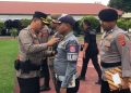 Kapolres Bone Bolango, AKBP Supriantoro saat menyematkan pita merah kepada perwakilan personel yang terlibat dalam Operasi Kepolisian Terpusat Lilin Otanaha 2025 dalam rangka Pelayanan Perayaan Natal 2025 dan Tahun Baru 2026 di Halaman Mapolres Bone Bolango, Jumat (19/12/2025). (F.Indra/Diskominfo)