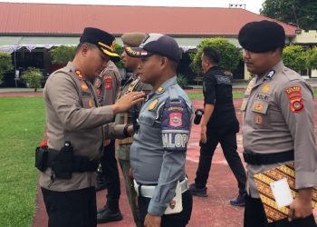 Kapolres Bone Bolango, AKBP Supriantoro saat menyematkan pita merah kepada perwakilan personel yang terlibat dalam Operasi Kepolisian Terpusat Lilin Otanaha 2025 dalam rangka Pelayanan Perayaan Natal 2025 dan Tahun Baru 2026 di Halaman Mapolres Bone Bolango, Jumat (19/12/2025). (F.Indra/Diskominfo)