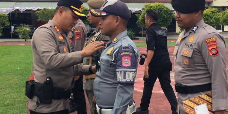 Kapolres Bone Bolango, AKBP Supriantoro saat menyematkan pita merah kepada perwakilan personel yang terlibat dalam Operasi Kepolisian Terpusat Lilin Otanaha 2025 dalam rangka Pelayanan Perayaan Natal 2025 dan Tahun Baru 2026 di Halaman Mapolres Bone Bolango, Jumat (19/12/2025). (F.Indra/Diskominfo)