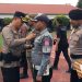 Kapolres Bone Bolango, AKBP Supriantoro saat menyematkan pita merah kepada perwakilan personel yang terlibat dalam Operasi Kepolisian Terpusat Lilin Otanaha 2025 dalam rangka Pelayanan Perayaan Natal 2025 dan Tahun Baru 2026 di Halaman Mapolres Bone Bolango, Jumat (19/12/2025). (F.Indra/Diskominfo)