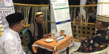 Bupati Bone Bolango, Ismet Mile, melakukan pembayaran zakat fitrah melalui Badan Amil Zakat Nasional (Baznas) Kabupaten Bone Bolango, Senin (16/3/2026) malam. (F.Indra/Diskominfo)