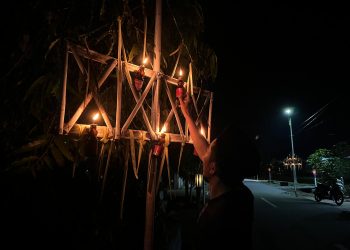 Abdullanto Ibrahim saat menyalakan lampu botol yang bergantungan di alikusu, Senin (16/3/2026) malam. (F.Indra/Diskominfo)