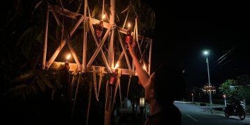 Abdullanto Ibrahim saat menyalakan lampu botol yang bergantungan di alikusu, Senin (16/3/2026) malam. (F.Indra/Diskominfo)