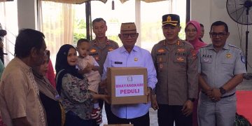 Bupati Ismet Mile saat menyerahkan paket bantuan kepada masyarakat. (F.Indra/Diskominfo)
