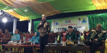 Bupati Ismet Mile didampingi Ketua T.P PKK Ruwaida Ismet Mile saat memberikan sambutan pada pelantikan pengurus dasawisma se-Kecamatan Suwawa Tengah, Rabu (10/6/2026) malam tadi. (F.Indra/Diskominfo)