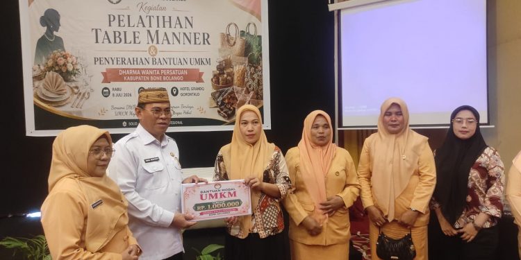 Sekda Iwan Mustapa didampingi Ketua DWP Bone Bolango, dr.Nurliana Ibrahim saat menyerahkan bantuan modal UMKM, Rabu (8/7/2026). (F.Munifa/Diskominfo)